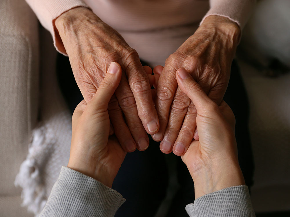 holding old woman's hands while grieving