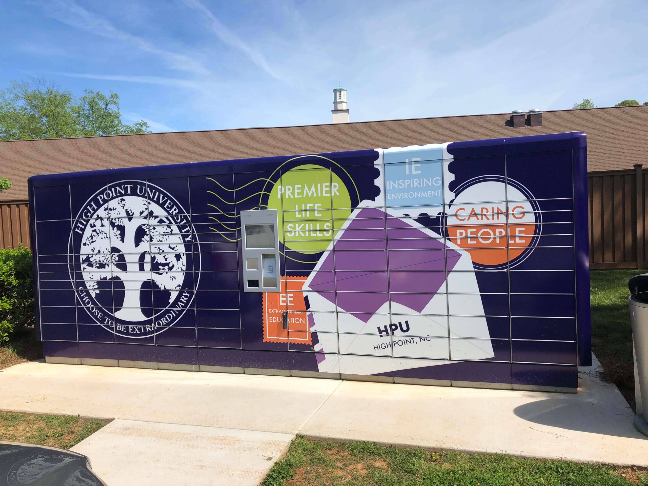 Colorful mural on a purple trailer featuring High Point University logo and phrases like 'Premier Life Skills' against a blue sky.
